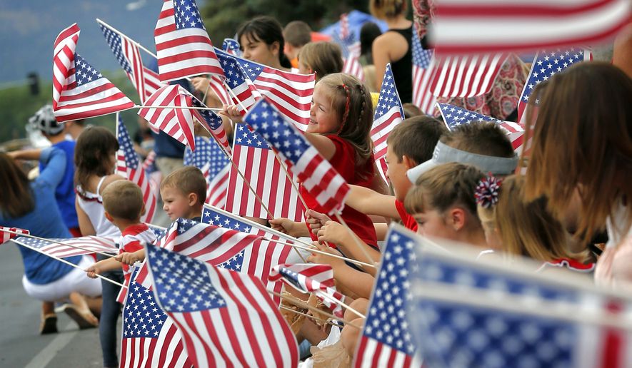 People wave flags as the Independence Day parade rolls down Main Street on July 4, 2014 in Eagar, Ariz. (Associated Press)
