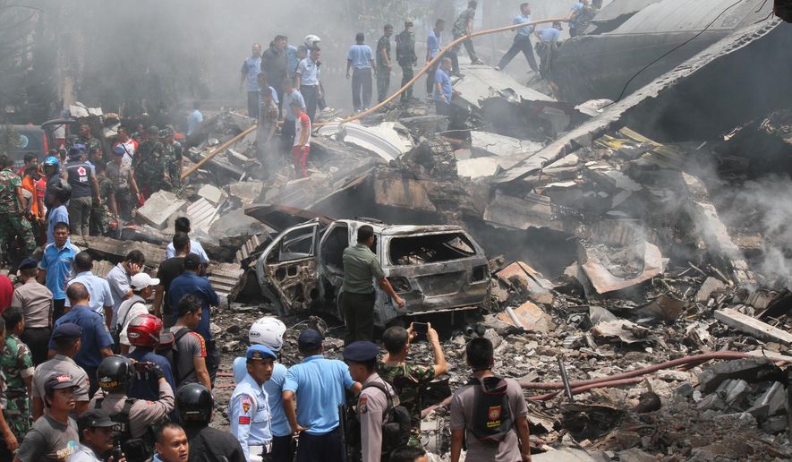 Firefighters and military personnel inspect the site where an Air Force cargo plane crashed in Medan, North Sumatra, Indonesia, Tuesday, June 30, 2015. An Indonesian Air Force Hercules C-130 plane with 12 crew aboard has crashed into a residential neighborhood in the country's third-largest city Medan. (AP Photo/Gilbert Manullang)
