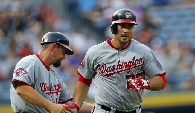 Washington Nationals first baseman Clint Robinson (25) is congratulated by third base coach Bob Henley (14) as he rounds third base after hitting a two-run home run in the first inning of a baseball game against the Atlanta Braves Tuesday, June 30, 2015, in Atlanta.  (AP Photo/John Bazemore)