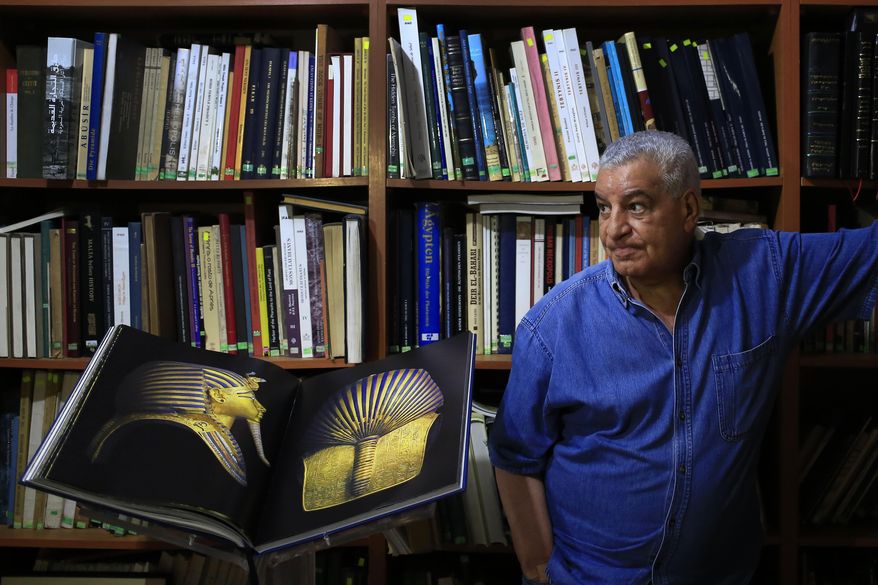 In this June 18, 2015 photo, Zahi Hawass, Egypt’s former head of antiquities, stands next to his new book, "The legend of Tutankhamun," as he speaks during an interview with The Associated Press in his office in Cairo. For more than a decade, he was the self-styled Indiana Jones of Egypt, presiding over its antiquities and striding through temples and tombs as the star of TV documentaries that made him an international celebrity. But four years after the 2011 uprising that toppled President Hosni Mubarak and nearly ended his own career, Hawass can be found in a cramped office, lamenting the state of the antiquities bureaucracy he once ruled like a pharaoh and dreaming of a new museum whose fate lies in limbo. (AP Photo/Hassan Ammar)