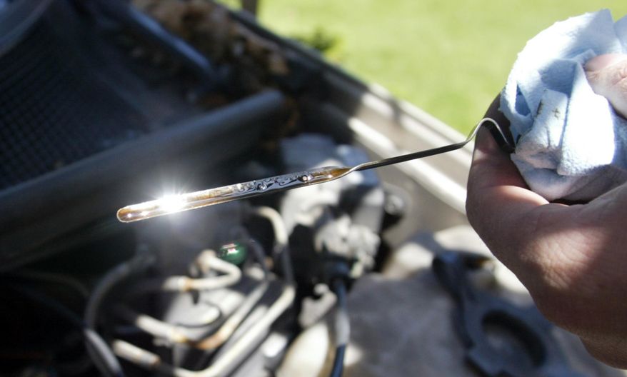 In this May 12, 2009, file photo, a man checks the oil on a car after changing it in North Muskegon, Mich. Newer cars aren’t supposed to burn oil, but Consumer Reports magazine found that some engines, mainly from Audi, BMW and Subaru, force their owners to add a quart as often as once a month. (Darren Breen/The Muskegon Chronicle via AP, File)
