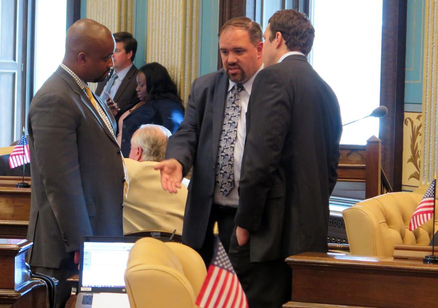Sen. Minority Leader Jim Ananich, D-Flint, center, talks with Sen. Bert Johnson, D-Highland Park, left, and Darin Ackerman, Gov. Rick Snyder’s deputy legislative affairs director, in the Michigan Senate chamber, Wedneday, July 1, 2015 in Lansing, Mich. The Republican-led Senate was deliberating Wednesday on a $1.5 billion plan to improve deteriorating Michigan roads by raising fuel taxes and redirecting money from elsewhere in the budget. (AP Photo/David Eggert)