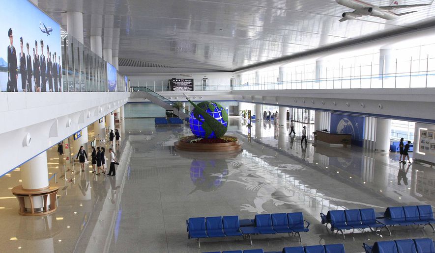 Staff members walk along the completed interiors of the new international airport terminal building at Pyongyang airport, Wednesday, July 1, 2015, in Pyongyang, North Korea. The unveiling Wednesday underscores an effort to attract more tourists and to spruce up the country ahead of the celebration of a major anniversary of the founding of its ruling Worker's Party in October this year. (AP Photo/Kim Kwang Hyon)