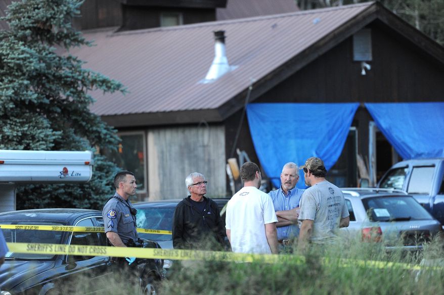 In this Monday, June 29, 2015, photo, from left, Routt County, Colo., Sheriff's Office Sgt. Stewart Curcio joins coroner Rob Ryg and Routt County Sheriff Garrett Wiggins in talking to residents, backs to camera, outside a home in which a 22-year-old woman was found dead in Clark, Colo., just north of Steamboat Springs, Colo. Authorities are seeking a 22-year-old man as a person of interest in the investigation into the death of the woman. (Scott Franz/Steamboat Today via the AP) MANDATORY CREDIT