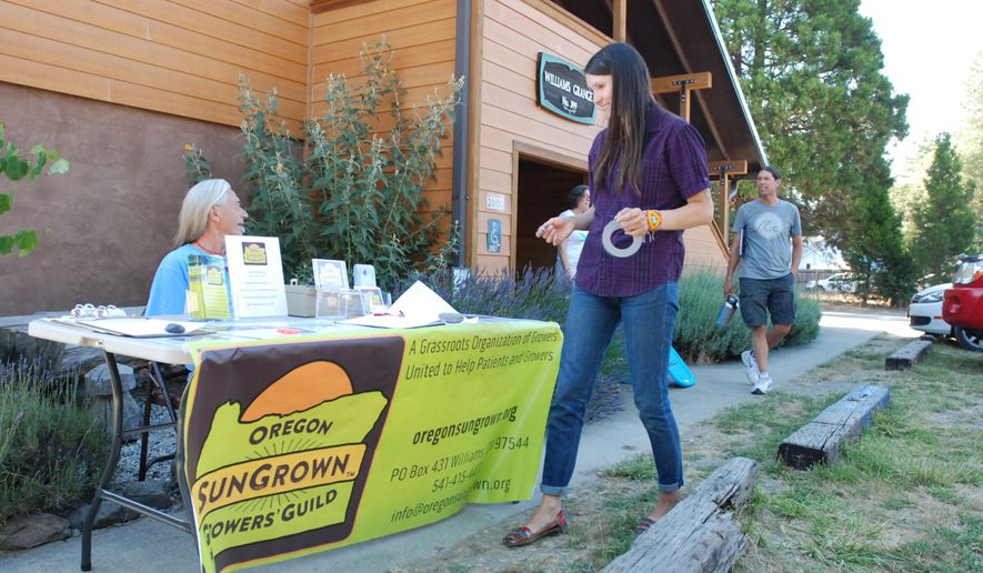 In this photo taken on June 25, 2015, Gina Erdmann, director of the Oregon SunGrown Growers' Guild, sets up a sign-in table for the monthly meeting of marijuana growers in the old Williams Grange in Williams, Ore. Since Oregon voters enacted Measure 91 legalizing recreational marijuana, veteran growers and newbies have been gathering monthly for updates on the regulatory picture and to share tips on growing healthy happy cannabis plants. Though many are hoping a new era of legal cannabis will be an economic boom for Oregon, experts suggest for many it will be a bust. Measure 91 starts going into effect July 1, when people can possess and grow amounts for personal use. But retail sales are months or more than a year away. (AP Photo/Jeff Barnard)