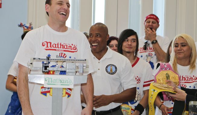 Brooklyn Borough President Eric Adams watches as Joey Chestnut, left, weighs in during a news conference to promote the upcoming Nathan&#x27;s Famous Fourth of July Hot-Dog Eating Contest, Friday, July 3, 2015, at Brooklyn Borough Hall in New York.  (AP Photo/Frank Franklin II)