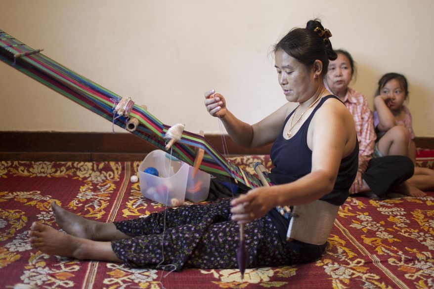 In this June 18, 2015, photo, Burmese master weaver Ku Mo uses the loom to backstrap weave in Waterloo, Iowa. Burmese immigrants have been able to resume the traditional art thanks to the support of several Cedar Valley organizations. (Matthew Putney/The Courier via AP)