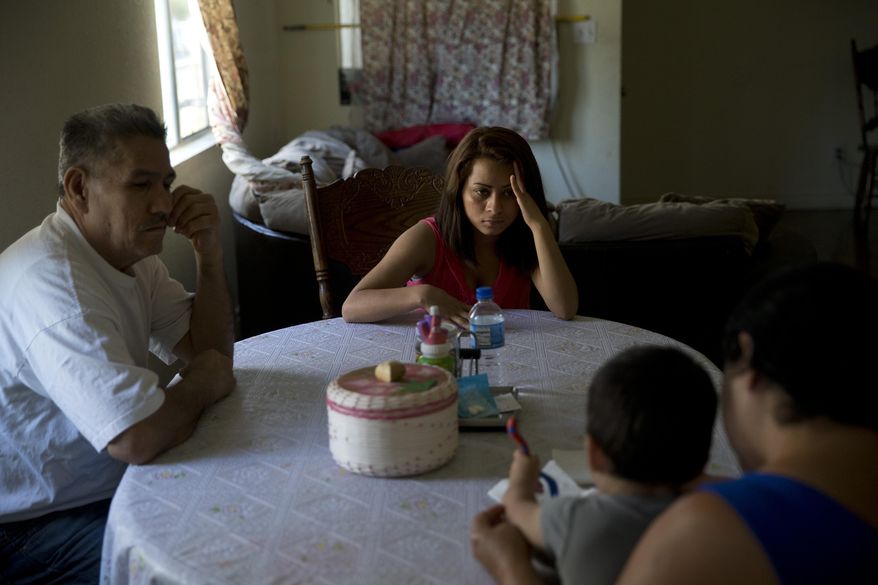 In this Monday, June 8, 2015 photo, 18-year-old Dunia Bueso, center, and her relative, Augustin Vargas, left, look at Bueso's 1-year-old son, Joshua Tinoco, foreground, sitting on the lap of Martina Perez, at their home in Los Angeles. At a brief hearing, a government lawyer tells the teenage mother that her son is an immigration enforcement priority for the United States and should be sent back to his native Honduras even though she is being allowed to stay and seek a green card. (AP Photo/Jae C. Hong)