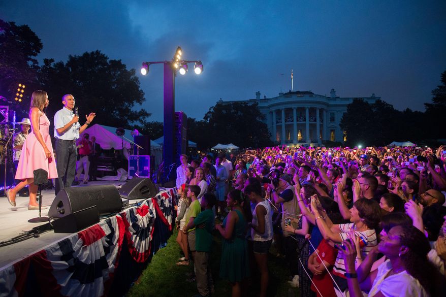 President Barack Obama, accompanied by first lady Michelle Obama, left, delivers remarks during an Independence Day celebration on the South Lawn at the White House in Washington, Saturday, July 4, 2015. (AP Photo/Andrew Harnik)