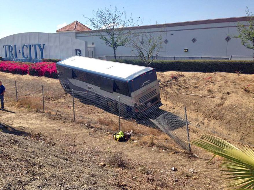 A Greyhound bus lies in a ditch after authorities say a passenger grabbed the steering wheel from the driver and forced it off a Southern California freeway in San Bernardino, Calif., Saturday, July 4, 2015. California Highway Patrol Sgt. Grady Stevens says the bus careened off Interstate 10, crashed through a chain link fence and into the ditch. Stevens said the man who caused the crash broke a bus window and ran several blocks before collapsing in a restaurant parking lot, where he was arrested. Of 22 people enroute from Phoenix to Los Angeles, five were taken to the hospital for minor injuries.(Greg Cappis(/The Sun via AP) MANDATORY CREDIT