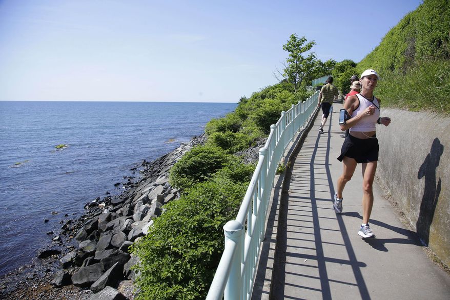 FILE - In this June 24, 2014 file photo, a runner and walkers travel along the Newport Cliff Walk, in Newport, R.I. The three-and-a-half mile walkway that borders the shore line, is now smoke-free. The city council voted June 10 in favor of an ordinance that banned smoking on city beaches, in the park and on the Cliff Walk. (AP Photo Stephan Savoia, File)