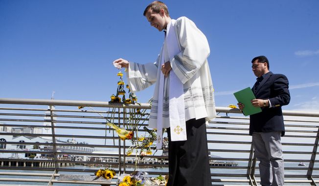 Father Cameron Faller of Restorative Justice Ministry drops holy water during a vigil for Kathryn Steinle, Monday, July 6, 2015, on Pier 14 in San Francisco. Steinle was gunned down while out for an evening stroll at Pier 14 with her father and a family friend on Wednesday, July 1. (AP Photo/Beck Diefenbach)