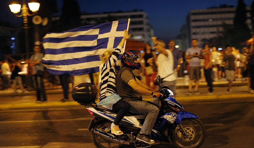 A supporter of the No vote waves a Greek flag after the first results of the referendum at Syntagma square in Athens, Sunday, July 5, 2015. (AP Photo/Emilio Morenatti)