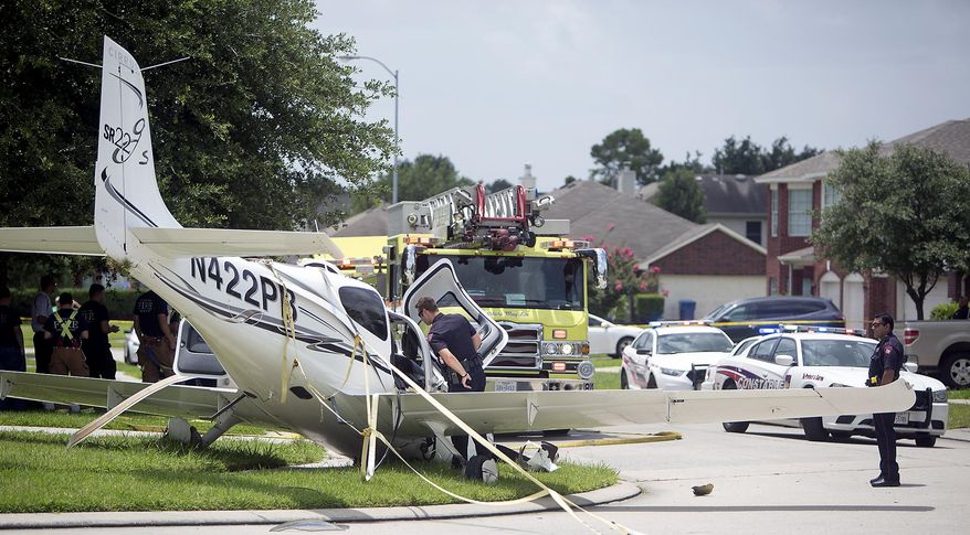 Authorities investigate after a plane made an emergency landing along Laurel Bank Way in North West Houston, Tuesday, July 7, 2015. Authorities say the pilot of the small plane reported engine trouble and deployed an emergency chute before landing in the Houston-area neighborhood. Authorities say the pilot and a passenger were being treated for minor injuries. (Cody Duty/Houston Chronicle via AP)