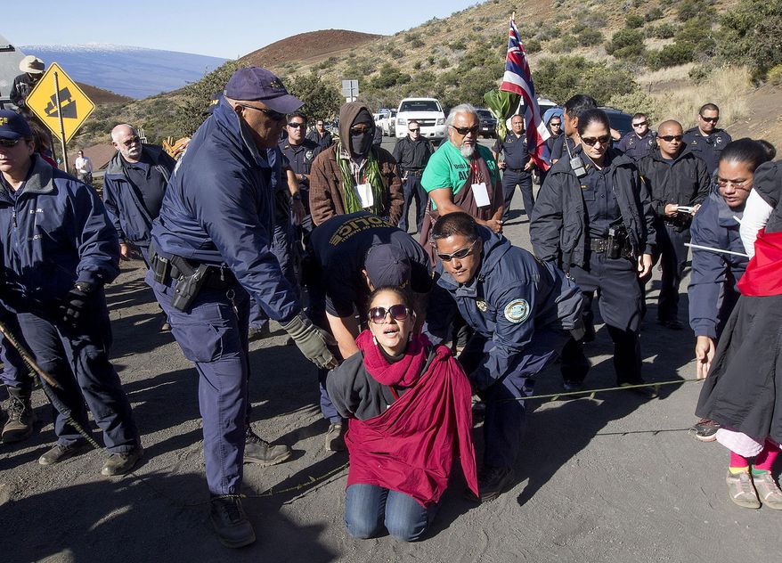 FILE - In this April 2, 2015, file photo, Department of Land and Natural Resources officers arrest a protester on the road to Thirty Meter Telescope building site on the summit of Mauna Kea in Hilo, Hawaii. Instead of a trial, most of the people arrested in April for blocking construction of a giant mountaintop telescope will likely participate in a Hawaiian culture-based form of mediation called hooponopono. (Hollyn Johnson/Hawaii Tribune-Herald via AP, File)