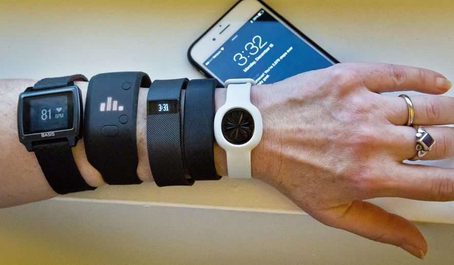 FILE - In this Dec. 15, 2014, file photo, fitness trackers, from left, Basis Peak, Adidas Fit Smart, Fitbit Charge, Sony SmartBand, and Jawbone Move, are posed for a photo next to an iPhone, in New York. Although sales of fitness trackers are strong, many of their owners lose enthusiasm for them once the novelty wears off. (AP Photo/Bebeto Matthews, File)