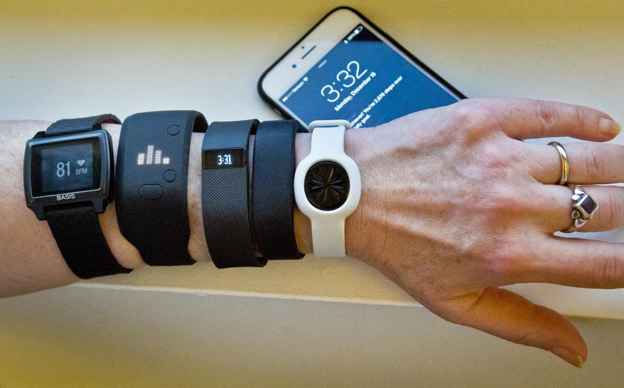 FILE - In this Dec. 15, 2014, file photo, fitness trackers, from left, Basis Peak, Adidas Fit Smart, Fitbit Charge, Sony SmartBand, and Jawbone Move, are posed for a photo next to an iPhone, in New York. Although sales of fitness trackers are strong, many of their owners lose enthusiasm for them once the novelty wears off. (AP Photo/Bebeto Matthews, File)