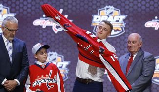 Jakub Vrana pulls on a Washington Capitals sweater after being chosen 13th overall during the first round of the NHL hockey draft, Friday, June 27, 2014, in Philadelphia. (AP Photo/Matt Slocum)