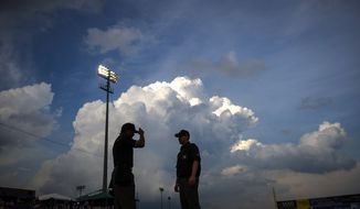 With storm clouds looming in the distance, umpires Erich Bacchus, left, and Chase Eade chat near the plate prior to the game, as the Frederick Keys host the Wilmington Blue Rocks at Nymeo Field at Harry Grove Stadium in Frederick, Md., Saturday, June 20, 2015. (Rod Lamkey Jr./Special for The Washington Times)