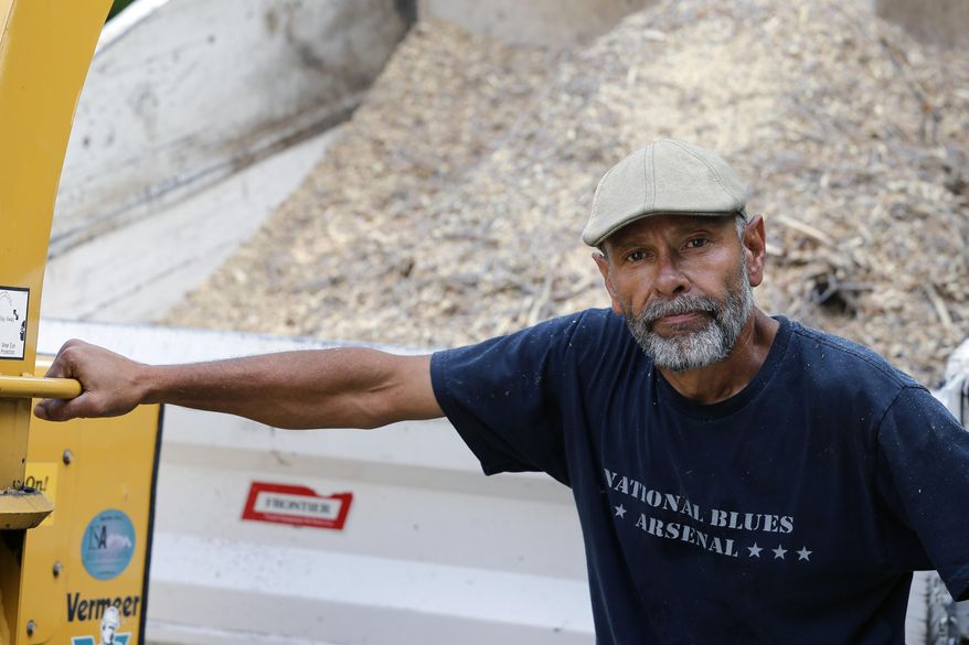 Alejandro Menocal, 53, a legal permanent resident in the United States who emigrated from Mexico in 1973, stands near one of the machines he operates as an employee of a tree trimming business, in Golden, Colo, Thursday, July 9, 2015. Menocal is one of a group of immigrants who were detained at a suburban Denver facility who are filing a lawsuit against GEO, the private company that held them, alleging that they were paid $1 a day to do janitorial work, sometimes under threat of solitary confinement. (AP Photo/Brennan Linsley)