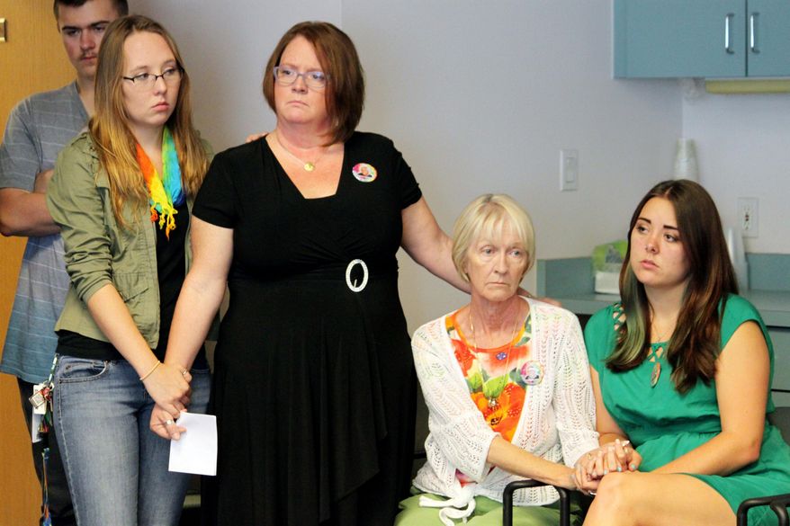 Family members of Steve Gerecke, who was gunned down in his driveway, hold hands during a news conference at police headquarters in Albuquerque, N.M., on Friday, July 10, 2015. A police task force tracked a stolen credit card and reviewed surveillance video from around the city before arresting six teens in connection with Gerecke's murder during a crime spree that targeted a northeast Albuquerque neighborhood in June. (AP Photo/Susan Montoya Bryan)