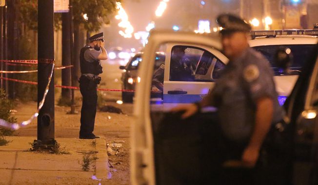 In this July 6, 2015, file photo, a Chicago police officer rests his hand on his forehead at the scene where a man was shot in the face in Chicago. Homicides and shooting incidents in Chicago are up roughly 20 percent from the same period last year.  (Anthony Souffle/Chicago Tribune via AP, File)