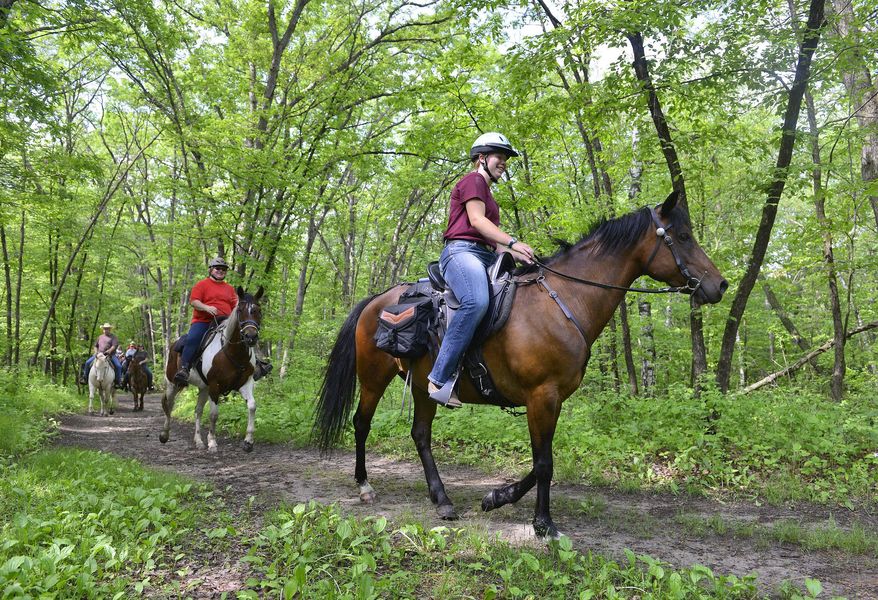 Sammy Schneider, 15, rides with her aunt, Christie Winkels during a trail ride with the Riverside Trail blazers at Lake Maria State Park on June 7, 2015, in rural Monticello, Minn. Riverside Trailblazers, which started in 2003, focuses on three things: trail rides, parades and event parking. (Kimm Anderson/The St. Cloud Times via AP) NO SALES