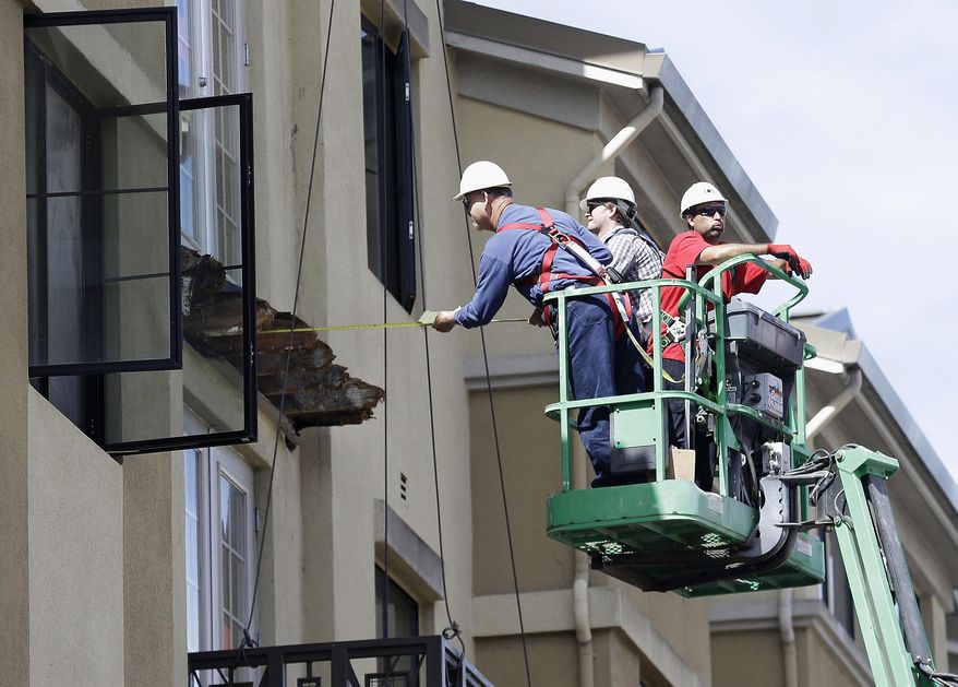 FILE- In this Wednesday, June 17, 2015 file photo, a worker measures near the remaining wood of an apartment building balcony that collapsed, killing six college students and injuring several others in Berkeley, Calif. The city of Berkeley has approved new building standards in the wake of the balcony collapse. The City Council voted Tuesday to require that new balconies are made of corrosion-resistant material and are ventilated to prevent a buildup of moisture. The council also mandated that all balconies be inspected within the next six months and every three years after that. (AP Photo/Jeff Chiu, File)