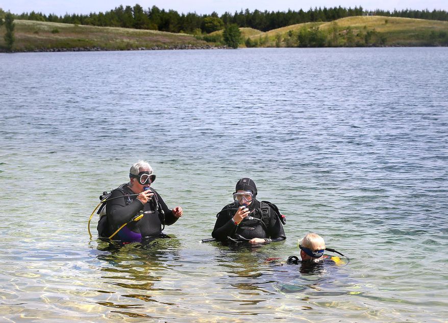 In this July 8, 2015 photo, Sarah Gillett, left, Karie Gillett, center, and Daphne Zeiler prepare to dive in Lake Wazee in Black River Falls, Wis. As the Midwest's premier site for scuba divers, Lake Wazee draws about 1,500 divers each year, according to Jackson County's forestry and parks department. But the high interest also means that the lake gets more than its share of fatal accidents. (Erik Daily/La Crosse Tribune via AP) MANDATORY CREDIT