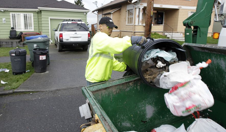 Anousone Sudettanh, an employee of Waste Management Inc., collects garbage for the city of Seattle on April 5, 2012. (Associated Press) **FILE**