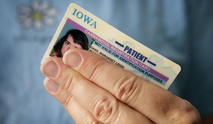 In this Tuesday, July 14, 2015 photo, Sally Gaer holds her daughter Margaret&#39;s medical cannabis patient card, in West Des Moines, Iowa. The state of Iowa paid $115,000 to create the cards. (AP Photo/Charlie Neibergall)