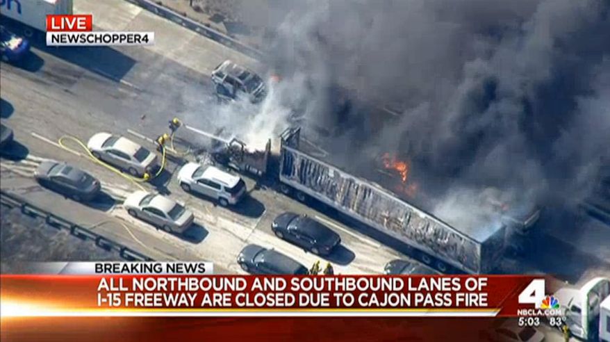 In this frame from video provided by NBC4, smoke rises from vehicles as a fast-moving wildfire swept across a freeway Friday, July 17, 2015, near Hesperia, Calif. The fire swept by desert winds burned on both sides of Interstate 15, the main connector between Southern California and Las Vegas that was crowded with vehicles. (NBC4 via AP) MANDATORY CREDIT