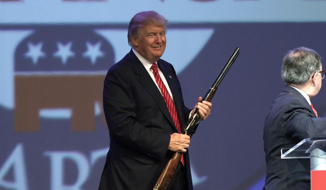 Republican presidential hopeful Donald Trump holds a Henry repeating rifle that was presented to him after speaking at the Republican Party of Arkansas Reagan Rockefeller dinner in Hot Springs, Ark., Friday, July 17, 2015. (AP Photo/Danny Johnston)