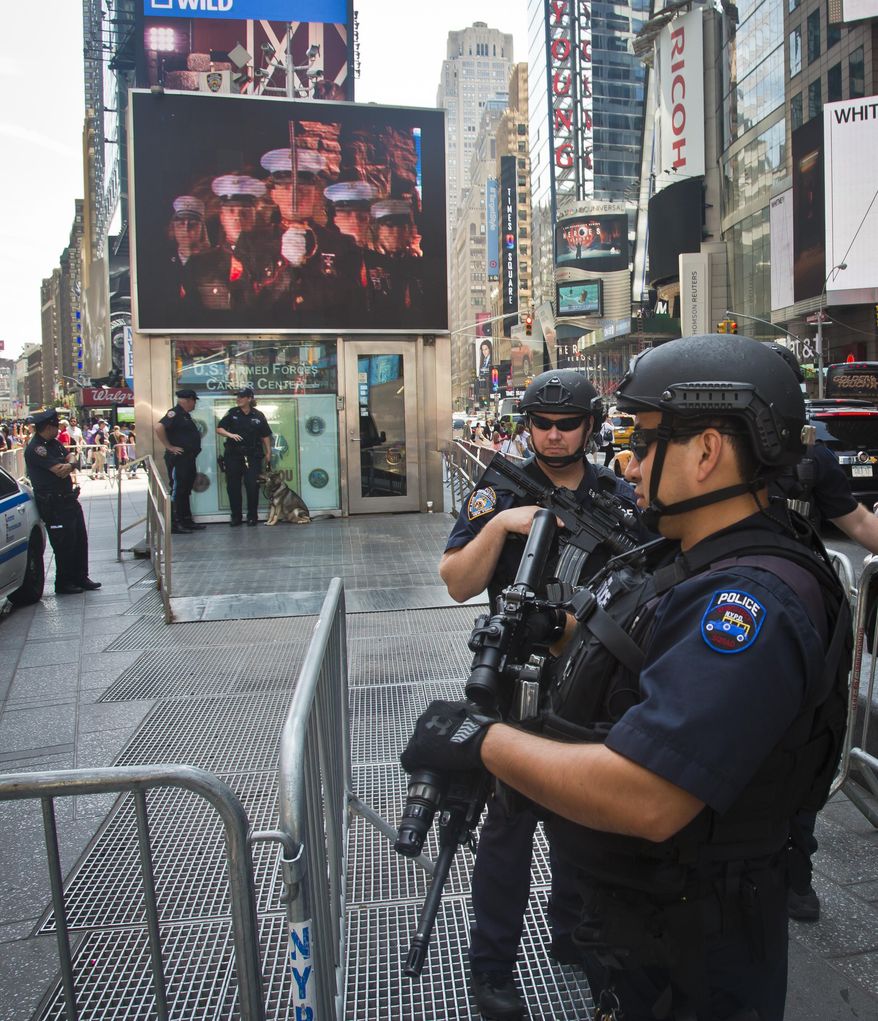 Officers with the NYPD anti-terrorism unit guard a military recruiting station in Times Square, Friday, July 17, 2015, in New York. Security at military recruiting and reserve centers will be reviewed in the aftermath of a deadly shooting in Tennessee. (AP Photo/Bebeto Matthews)