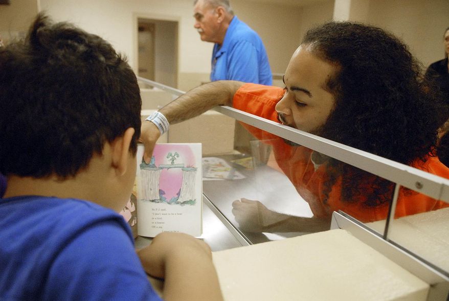In this photo taken on Monday, July 13, 2015, inmate Carlos Diaz-Hernandez reads with his children, who are currently in foster care, during the Reading is Fun Program (RIF) at the Schenectady County Jail's visitation room, in Schenectady, N.Y. (Erica Miller /The Daily Gazette via AP) TROY, SCHENECTADY; SARATOGA SPRINGS; ALBANY AND AMSTERDAM OUT; MANDATORY CREDIT