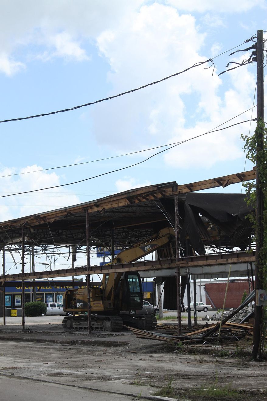 In this June 26, 2015 photo, a trackhoe razes the building from the site of the former Greenville Lumber Company in Greenville, Miss. Greenville Mayor John Cox said, the city will charge the cost of demolition to property taxes. (Bill Johnson /The Delta Democrat-Times via AP) MANDATORY CREDIT