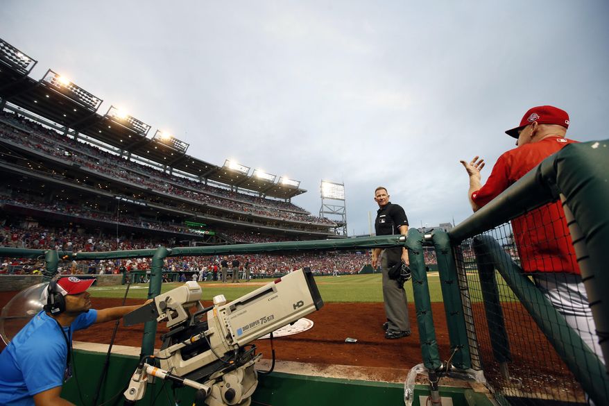Home plate umpire Jim Wolf (28) talks with Washington Nationals manager Matt Williams (9) after some of the lights went out and play was halted during the fourth inning of a baseball game against the Los Angeles Dodgers at Nationals Park, Friday, July 17, 2015, in Washington. (AP Photo/Alex Brandon)