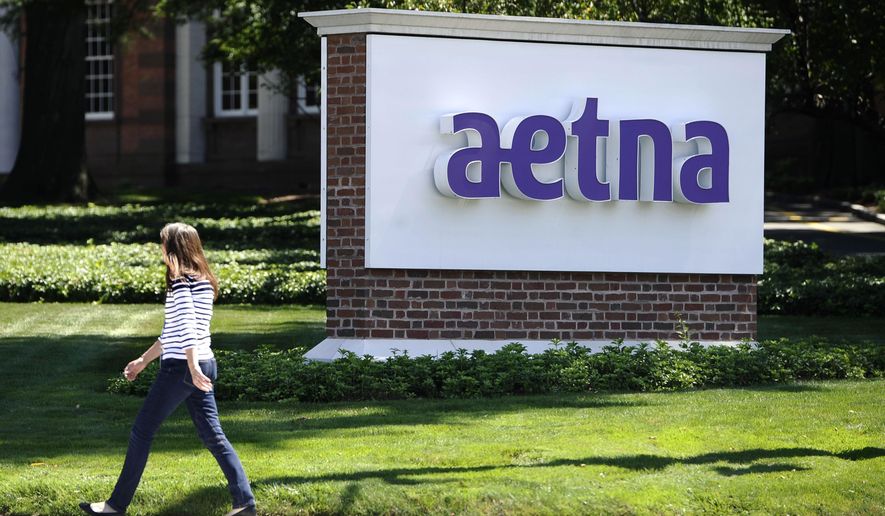 In this Tuesday, Aug. 19, 2014 file photo, pedestrian walks past a sign for health insurer Aetna Inc., at the company headquarters in Hartford, Conn. (AP Photo/Jessica Hill, File)