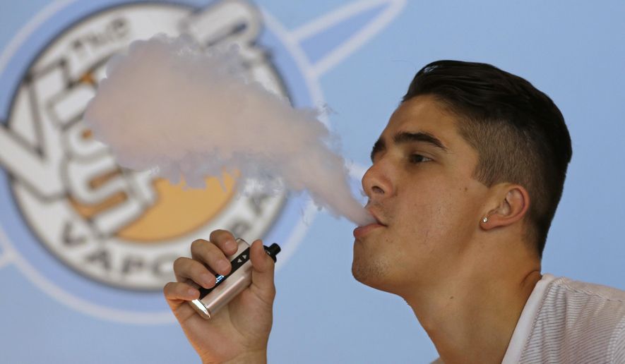 Will Braaten exhales vapor from an e-cigarette at the Vapor Spot, in Sacramento, Calif.  As e-cigarettes rise in popularity, the number of “vape shops” are  increasing for customers who gather to inhale doses of nicotine through a flavored vapor solution. (AP Photo/Rich Pedroncelli)