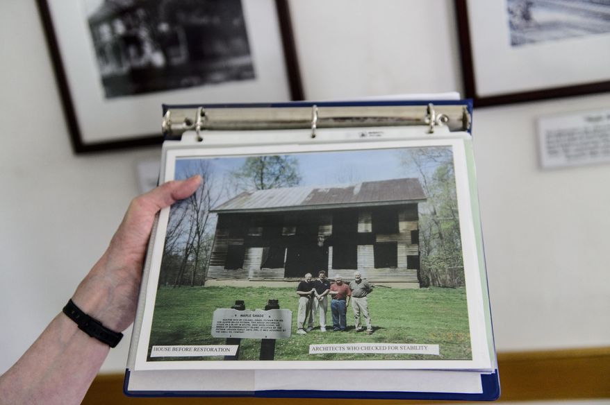 ADVANCE FOR MONDAY JULY 20, 2015 AND THEREAFTER - In this Tuesday July 7, 2015 photo, Mary Jane Spurgeon, a docent for the Putnam-Houser House and a member of the Blennerhassett Historic Foundation, holds up a picture of the house, built in 1802, before it was restored to it's original condition at Blennerhassett Island Historical State Park in Parkersburg, W. Va. With help from the Blennerhassett Historical Foundation, that raised money to repair the house, the island began opening up the restored house for small tours in 2009. (Sam Owens/Charleston Gazette via AP)