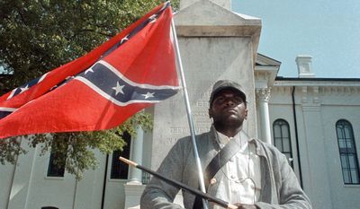 In this May 8, 2000, file photograph, Anthony Hervey holds a Confederate flag while standing underneath the Confederate monument in Oxford, Miss. The Highway Patrol says 49-year-old Hervey was killed Sunday, July 19, 2015, when his 2005 Ford Explorer left the roadway and overturned on Mississippi Highway 6 in Lafayette County. (Bruce Newman/The Oxford Eagle via AP, File)