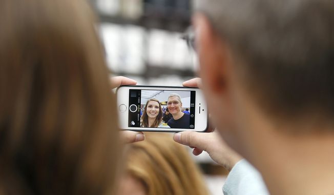 In this Sept. 19, 2014, file photo, Apple CEO Tim Cook, right, takes a photo with an Apple employee during the launch and sale of the new iPhone 6 at an Apple store in Palo Alto, Calif. (AP Photo/Tony Avelar, File)