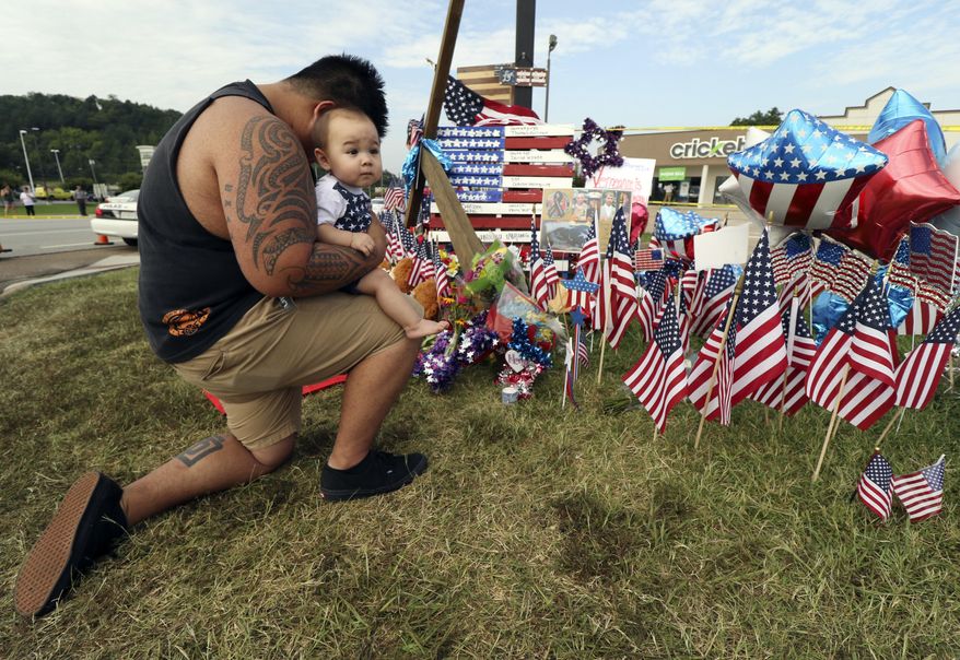 Bryan Thaboua kneels with his 8-month-old son Cooper Thaboua on Monday, July 20, 2015, in front of the Lee Highway memorial for last Thursday&#39;s Chattanooga, Tenn., shooting victims. Muhammad Youssef Abdulazeez attacked two military facilities on Thursday in a shooting rampage that killed several. (Dan Henry/Chattanooga Times Free Press via AP)