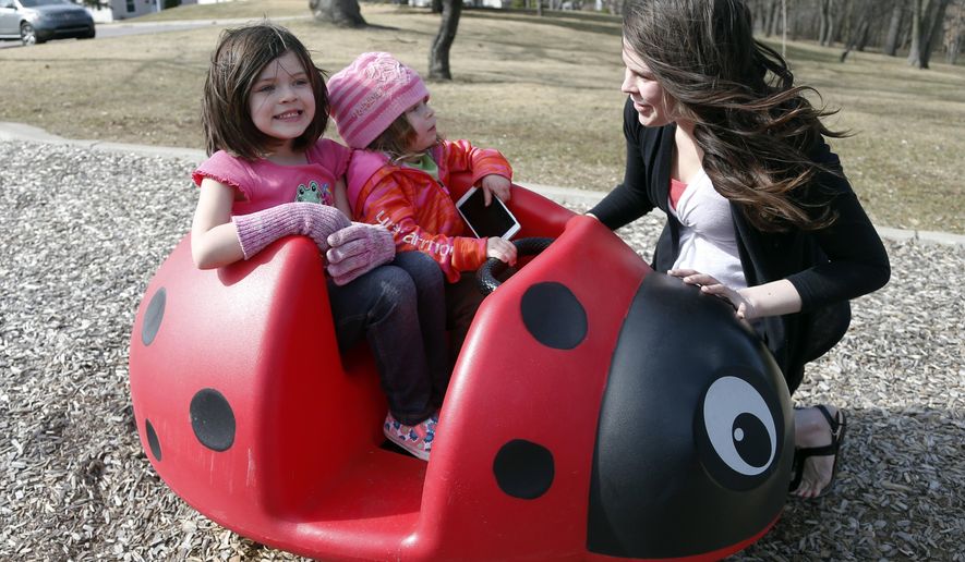 Michelle Halonen, enjoying the warm day with daughters Madilyn, left, and Ellie at a park in St. Louis Park, Minn., works full time at a gas station and still struggles to support her two young daughters. A new report on child welfare that found more U.S. children living in poverty than before the Great Recession belies the fanfare of the nation's economic turnaround. (AP Photo/Jim Mone, File)
