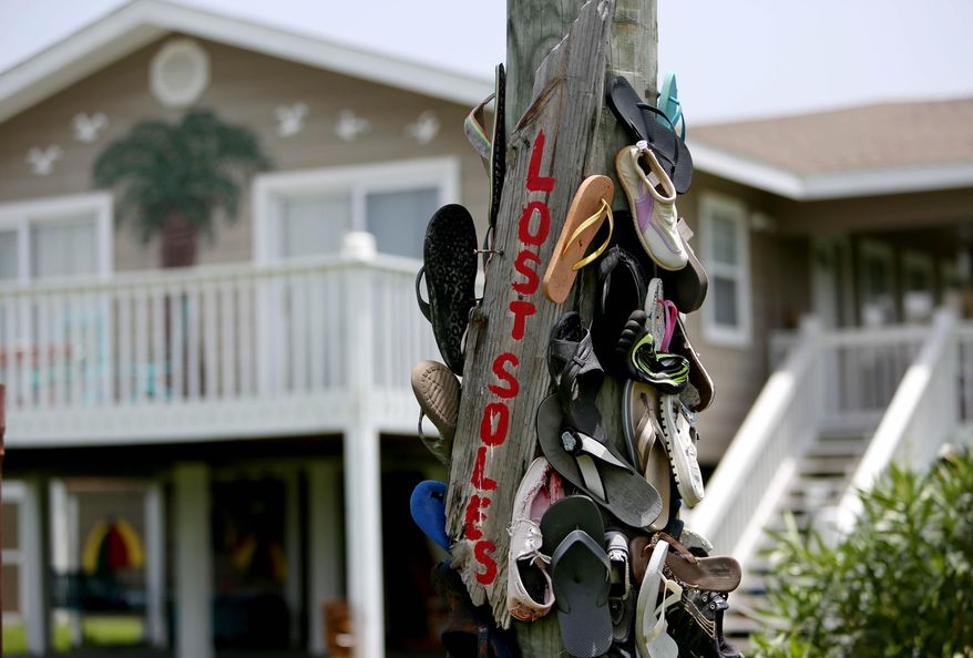 ADVANCE FOR SUNDAY, JULY 26, 2015, AND THEREAFTER - A utility pole is decorated with shoes and sandals in the Emerald Beach community, Wednesday, July 8, 2015, in Port Bolivar, Texas. New developments planned for Bolivar Peninsula, luxury houses surrounded by lush grounds and an elevated pool and a large marina, may be the future of the once rustic, fishing village along the 30-mile stretch of Highway 87. (Gary Coronado/Houston Chronicle via AP)