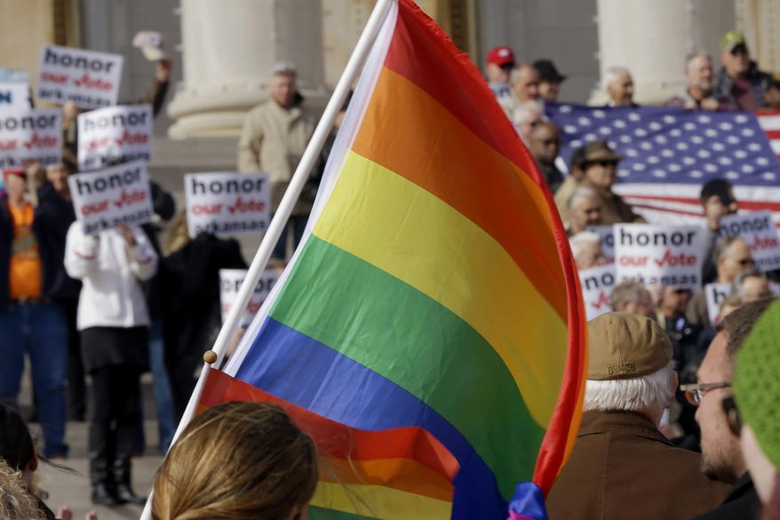 In this file photo taken Nov. 19, 2014, supporters of Arkansas' law banning same sex marriage, top, hold a rally as a protestor waves a rainbow flag at the Arkansas state Capitol in Little Rock, Ark. The Arkansas Supreme Court voted on a narrow part of the state's case over gay marriage in June, 2015, but only planned on issuing that decision if the nation's highest court didn't legalize same-sex marriage, a justice said Thursday, July 23, 2015. (AP Photo/Danny Johnston, File)