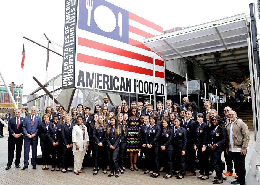 FILE - In this Thursday June 18, 2015 file photo, U.S. first lady Michelle Obama, center, poses for a photo with workers of the United States pavilion at the 2015 Expo in Rho, near Milan, Italy. Culinary tourists are pushing growth in foreign tourism to the United States, which is transforming its image as a fast-food mecca to a land of regional tastes and dishes, said officials visiting the Expo 2015 world’s fair focusing on food this week. (AP Photo/Antonio Calanni, File)