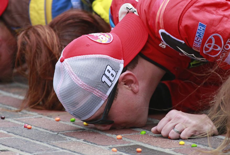 Kyle Busch kisses the bricks on the start/finish line after winning the NASCAR Brickyard 400 auto race at Indianapolis Motor Speedway in Indianapolis, Sunday, July 26, 2015. (AP Photo/R Brent Smith)