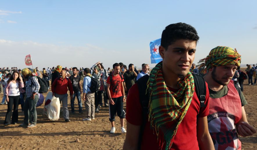 About 1,000 Kurdish activists from Istanbul who arrived in response to a call for mass mobilization by the imprisoned leader of the PKK rebel group, Abdullah Ocalan, gather at the border near Suruc, Turkey, on Sept. 25, 2014. (Associated Press)
