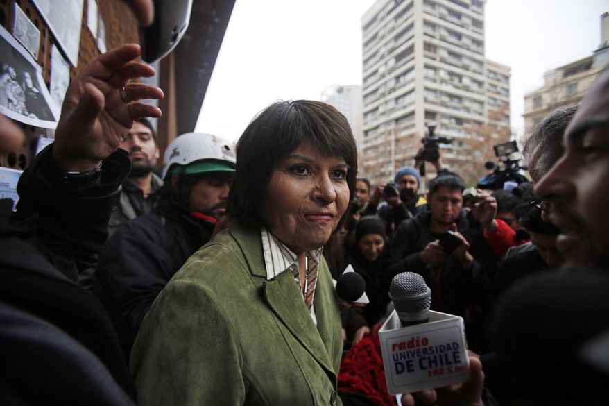 Carmen Quintana attends a tribute for slain photographer Rodrigo Rojas, outside the Gabriela Mistral museum, in Santiago, Chile, Tuesday, July 28, 2015. During a street demonstration on July 2, 1986, soldiers doused Rojas and then 18-year-old Quintana with gasoline and set them ablaze. Rojas died four days later. Quintana survived and underwent lengthy treatment for severe burns at a Canadian hospital. Her scarred face later became a symbol of the atrocities committed by Pinochet's dictatorship. A Chilean judge last week charged seven former members of the military in the burning death of Rojas, and four other ex-soldiers were being questioned on Monday. (AP Photo/Luis Hidalgo)